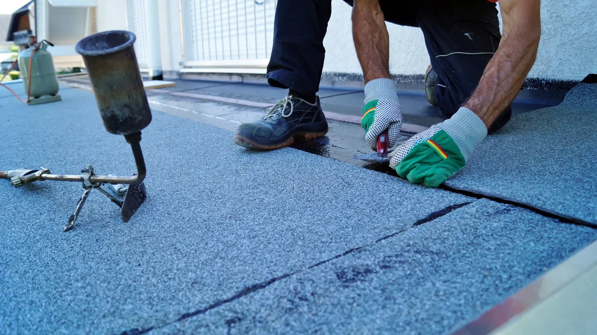 Stock image of a roofer fitting felt flat roofing